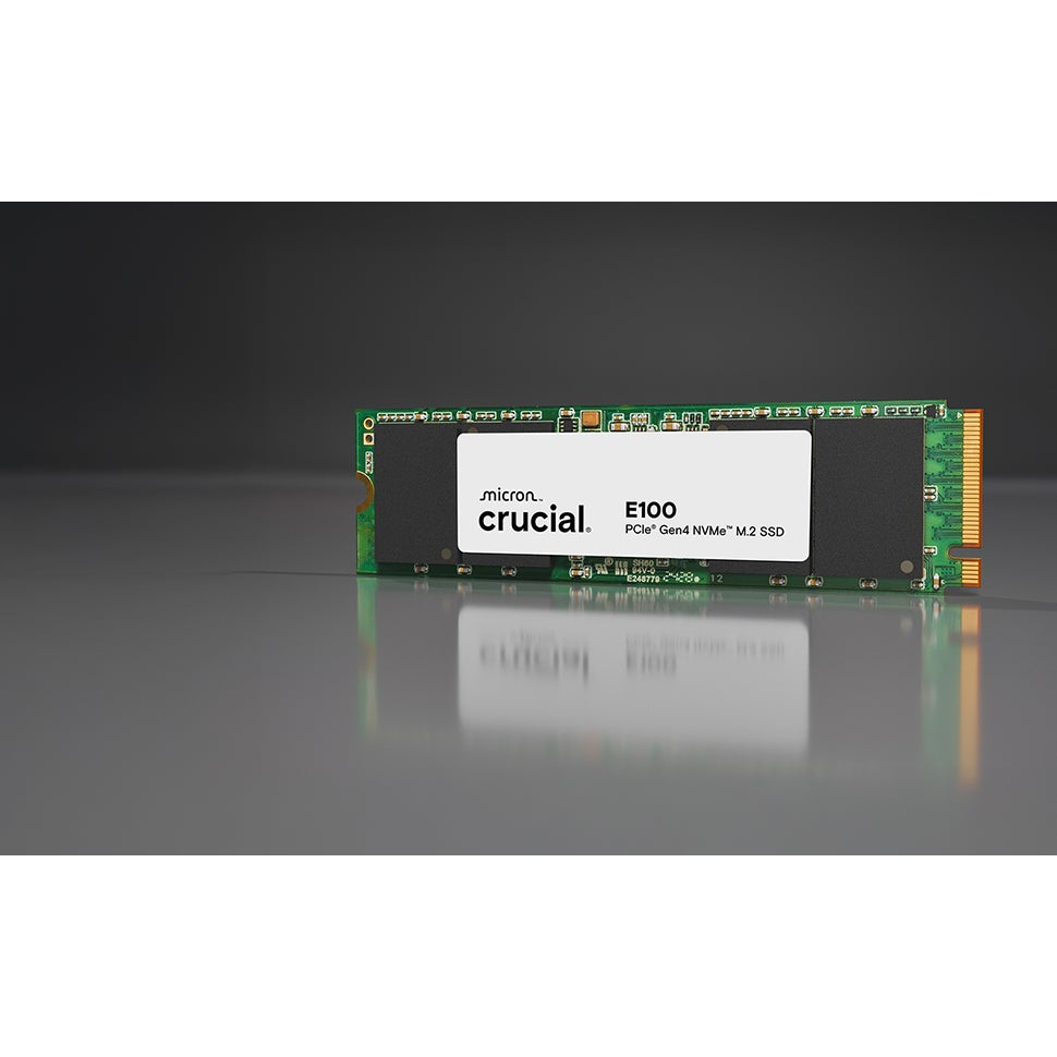 Crucial E100 PCIe Gen4 NVMe M.2 SSD with a green circuit board and white label, reflecting on a glossy surface.