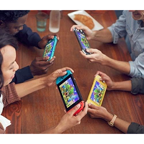 People playing with colorful handheld gaming devices on a wooden table.